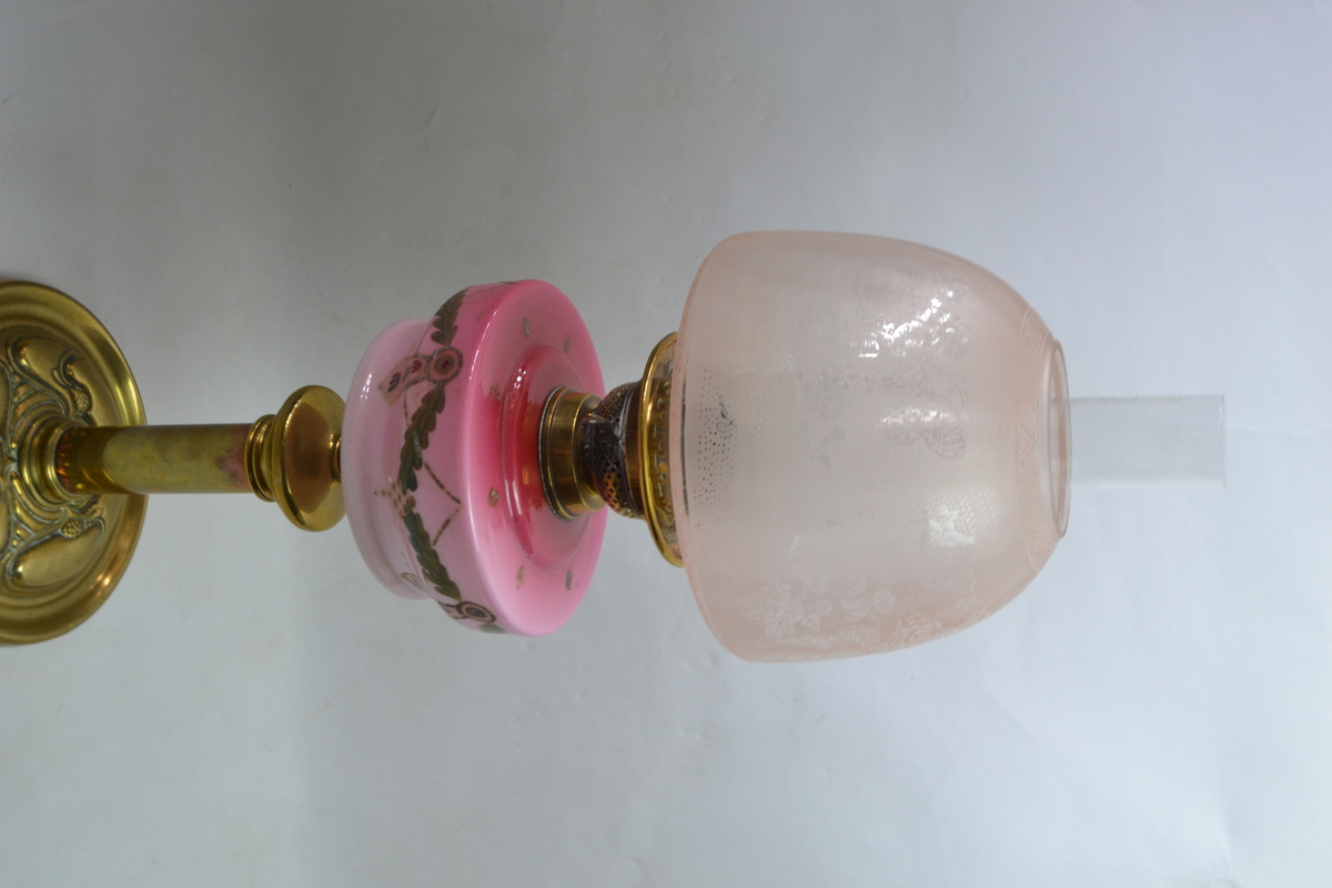 An Art Nouveau Brass Based Oil Lamp With Enamel Painted Cranberry Ceramic reservoir